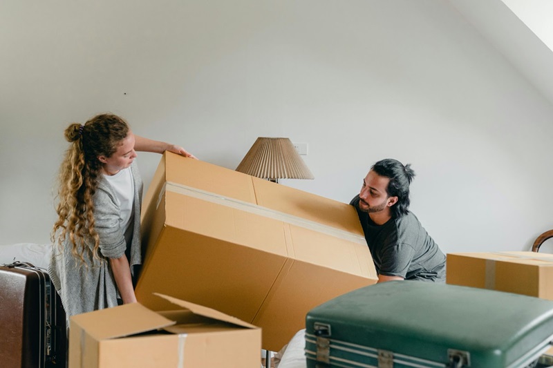 two people picking up a large moving box